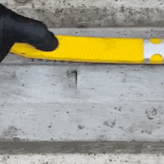 Worker applying adhesive sealant tape to repair a crack in a concrete surface using gloved hands
